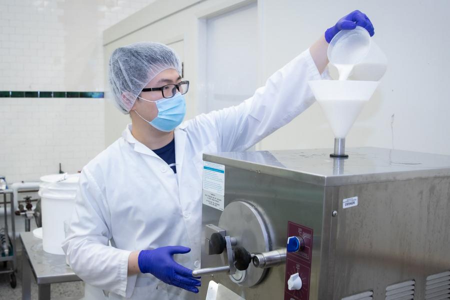 A dairy pilot plant technician pours ice cream mix into machine.